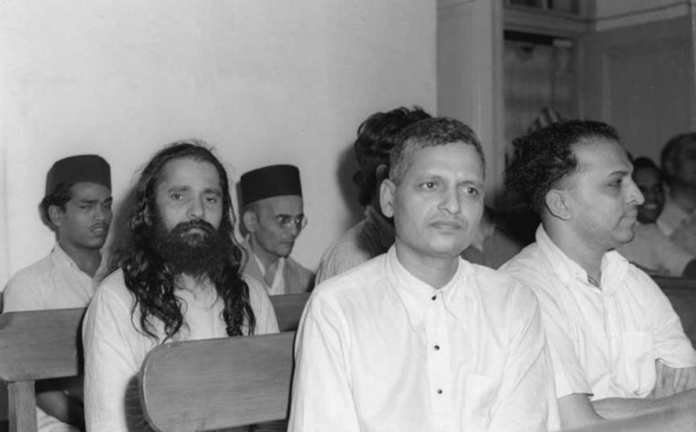 Archival photograph of Nathuram Godse and other accused in the Mahatma Gandhi assassination case during court proceedings.