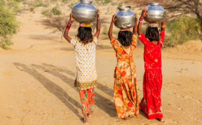 Village girls carry water pots on their heads as they walk home in rural India.